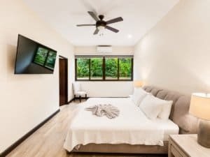 Bright bedroom with garden view, TV, ceiling fan, and cozy bed in Dominical.