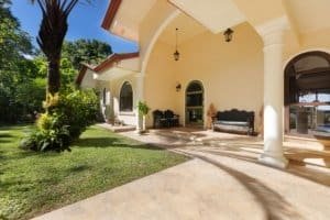Elegant Costa Rican home with spacious porch, lush garden, and mountain view.