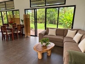 Bright living room with large glass doors opening to lush greenery in Dominical.
