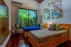 Dominical real estate cozy shared bedroom with two beds and tropical artwork.