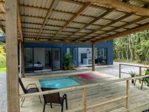 Creekside patio with small pool, covered veranda and sliding glass doors to modern house.