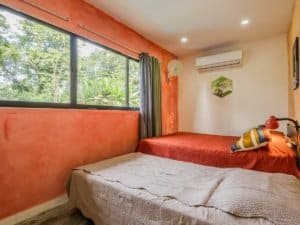 Interior of a bedroom with large window, green view, and colorful decor.