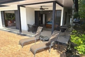 Outdoor patio with lounge chairs and covered seating in front of a modern home.