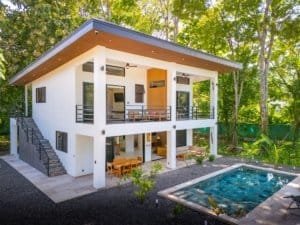 Two-story white villa with pool and lush greenery, Costa Rica real estate.