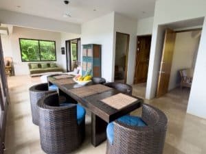 Modern living and dining area with ocean view, pool, and garden in Dominical.