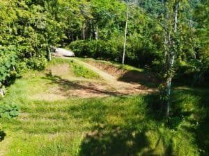 Dominical real estate: elevated land with surrounding trees, grass, and dirt road path.