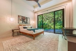 Ocean view bedroom in Costa Rica villa with sliding glass doors to lush greenery.