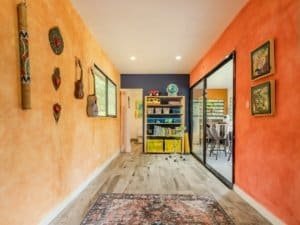 Vibrant living space with orange and yellow walls, artwork, and a view into the dining area.