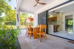 Condominium outdoor dining area with wooden table and chairs, sliding glass doors to kitchen.