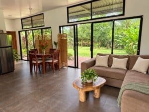 Bright living room with large windows overlooking lush garden in Dominical.