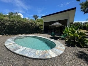 Dominical real estate: modern house with circular stone pool and umbrella.