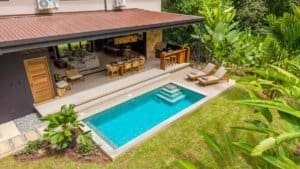 Luxurious tropical outdoor living area with modern pool and lounge chairs.