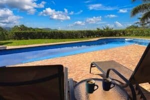 Poolside seating with two mugs overlooking a tropical landscape and swimming pool in Dominical.