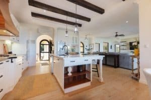 Spacious modern kitchen with island, white cabinets, and wooden accents in Costa Rica home.