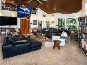 Interior of a large, well-furnished living room with tropical decor and ocean view.
