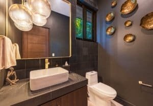 Modern bathroom with vessel sink, dark tiles, and decorative wall plates.