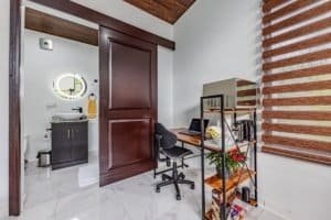 Compact home office with a desk, chair, and shelving unit near a striped window shade.