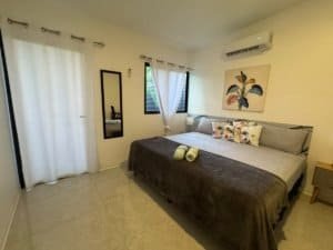 Bright bedroom with king bed, white curtains, and tropical wall art in Dominical Costa Rica.
