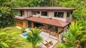 Dominical real estate: modern two-story jungle villa with pool and patio, surrounded by lush green.