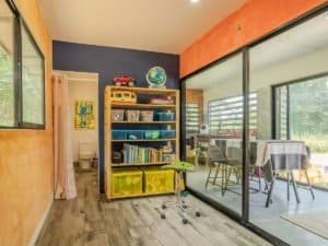 Interior of a Costa Rican home with colorful walls, bookshelf, and patio view.