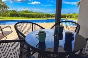Outdoor seating by pool and view of the ocean and blue sky.