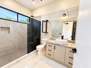 Bright modern bathroom with double vanity, vessel sink, and glass-enclosed walk-in shower.