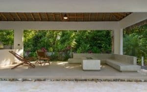 Modern tropical patio with lounge chairs, minimalist seating, and lush Costa Rica garden view.