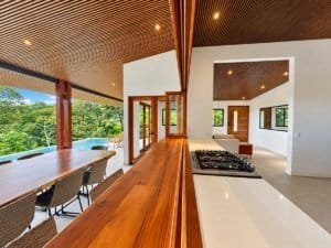 Dominical real estate: modern open-concept kitchen and balcony with lush greenery outside.