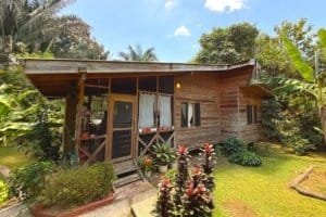 Charming wooden jungle hotel with lush tropical garden and river setting.