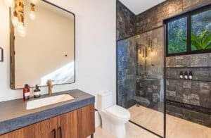 Modern bathroom with wooden vanity, large mirror, and glass-enclosed walk-in shower.