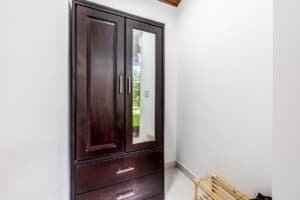 Dark wood cabinet with mirrored door in bright hallway, Costa Rica real estate image.