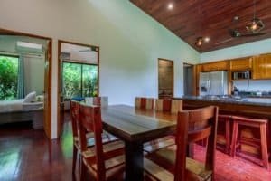 Turn-key 2-bedroom coastal living area with wooden dining table and open kitchen in Dominical, Costa.