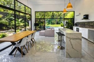 Bright modern open-concept kitchen and dining area with large windows and pool view.