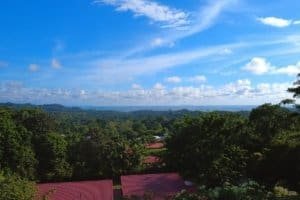 Panoramic ocean view over lush green forest and red-roofed homes in Costa Rica.