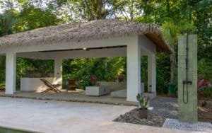 Outdoor living area with thatched roof structure, modern seating and tropical plants in Costa Rica.