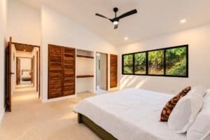 Bright bedroom with large window overlooking lush jungle in Dominical real estate.