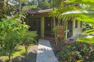 Beautiful jungle hotel entrance with lush greenery and colorful flowers in Dominical.