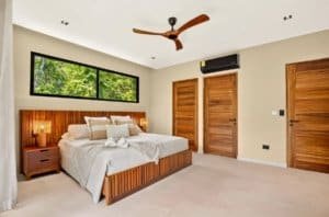 Luxurious tropical bedroom with king bed, wooden headboard, and natural light.