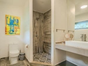 Contemporary bathroom with walk-in shower, toilet, and vanity with mirror.