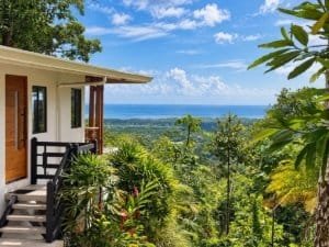 Dominical real estate ocean view home with lush tropical garden and distant sea horizon.