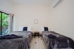 Two twin beds with plush blankets and pillows in a bright room.