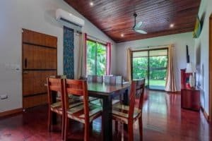Coastal living dining area with wooden table and chairs in a bright room.