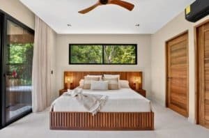 Bright master bedroom with wooden bed frame, large window, and natural light.