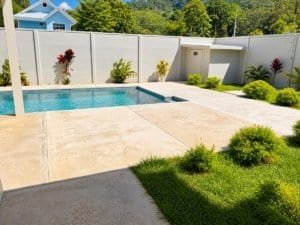 Costa Rica pool area with modern fenced yard and surrounding landscaping.