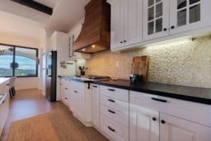 Modern kitchen with white cabinets, black countertops, and mountain view.