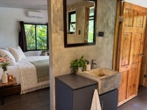 Interior view of a tropical home with a bedroom and rustic sink area near the beach.