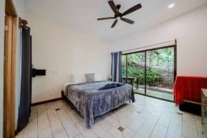 Furnished bedroom with garden view, sliding glass door, and ceiling fan in Dominical.