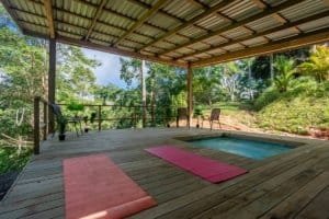 Creekside deck with pool, yoga mats, and forest backdrop in Dominical.
