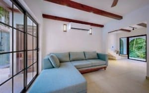 Bright living room with blue sectional sofa and exposed wooden beams.