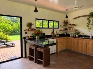 Modern kitchen with open door to lush green outdoor space in Dominical.